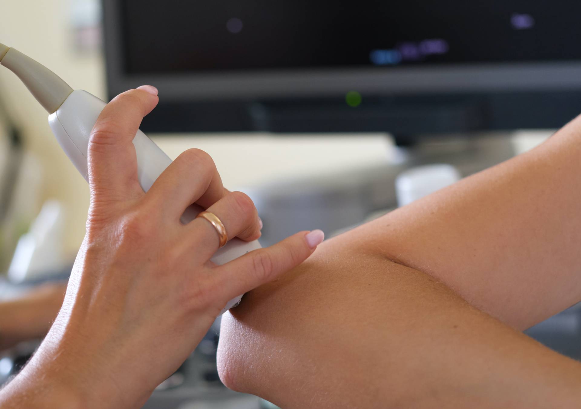 Doctor conducts ultrasound examination of elbow joint in clinic closeup