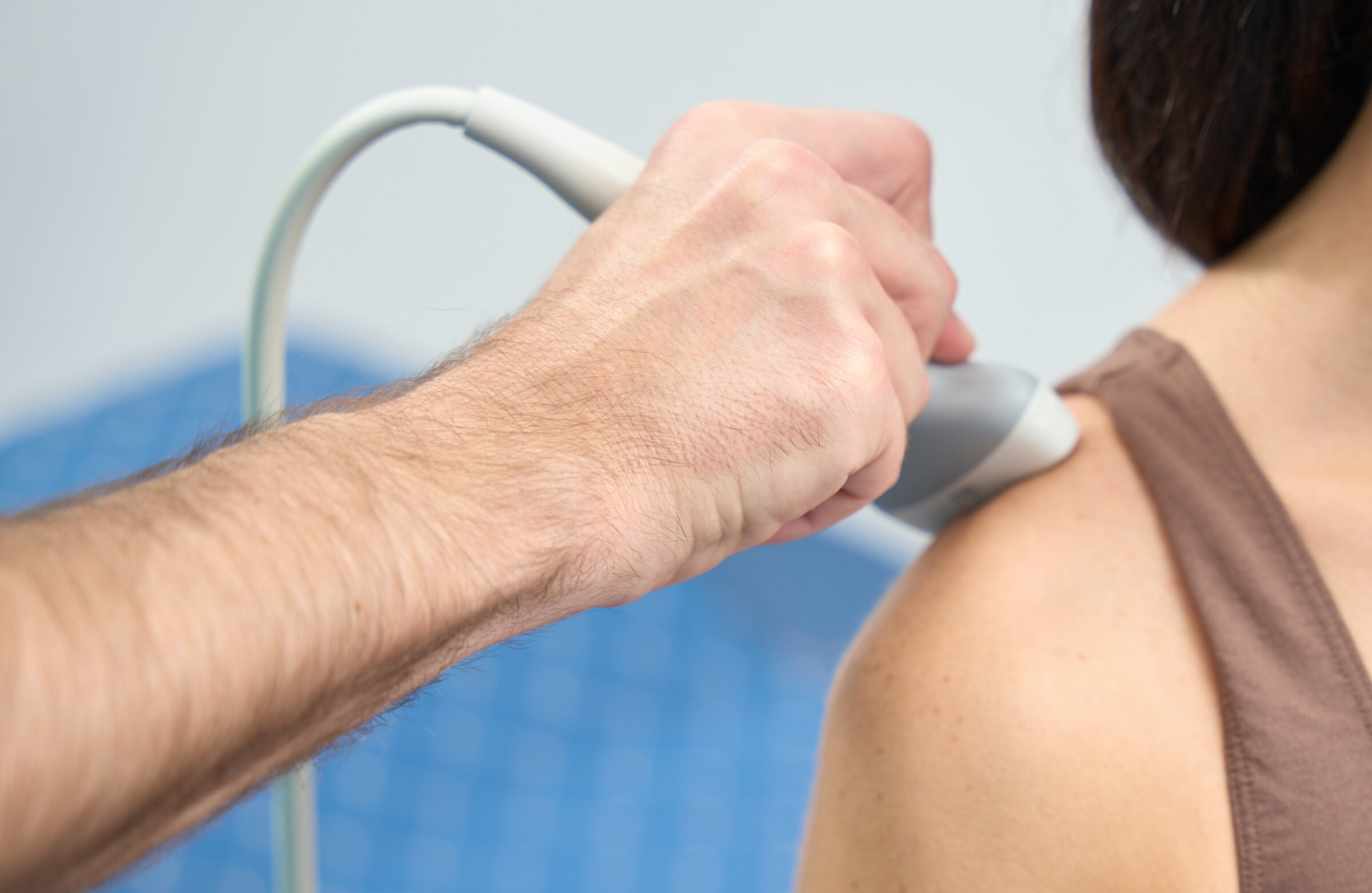 Woman is undergoing shoulder examination on clinic with ultrasound machine