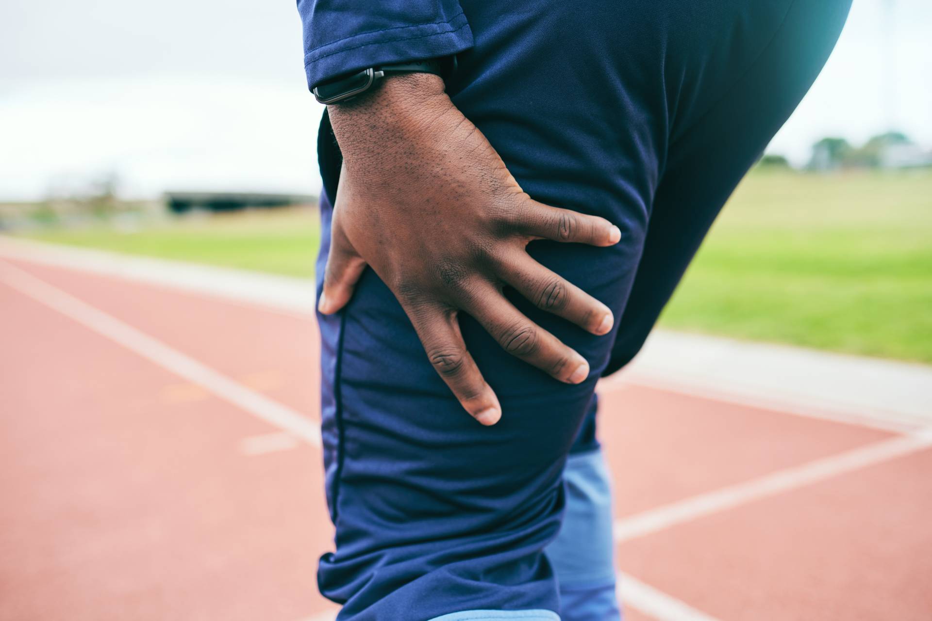 Leg pain, injury and black man runner, fitness and race in stadium, training for marathon or relay